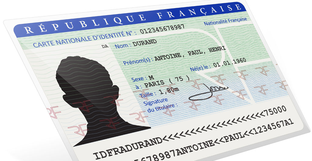 Gros plan sur une main tenant une carte Vitale et une carte d'identité française posées sur une table avec des documents floutés en arrière-plan